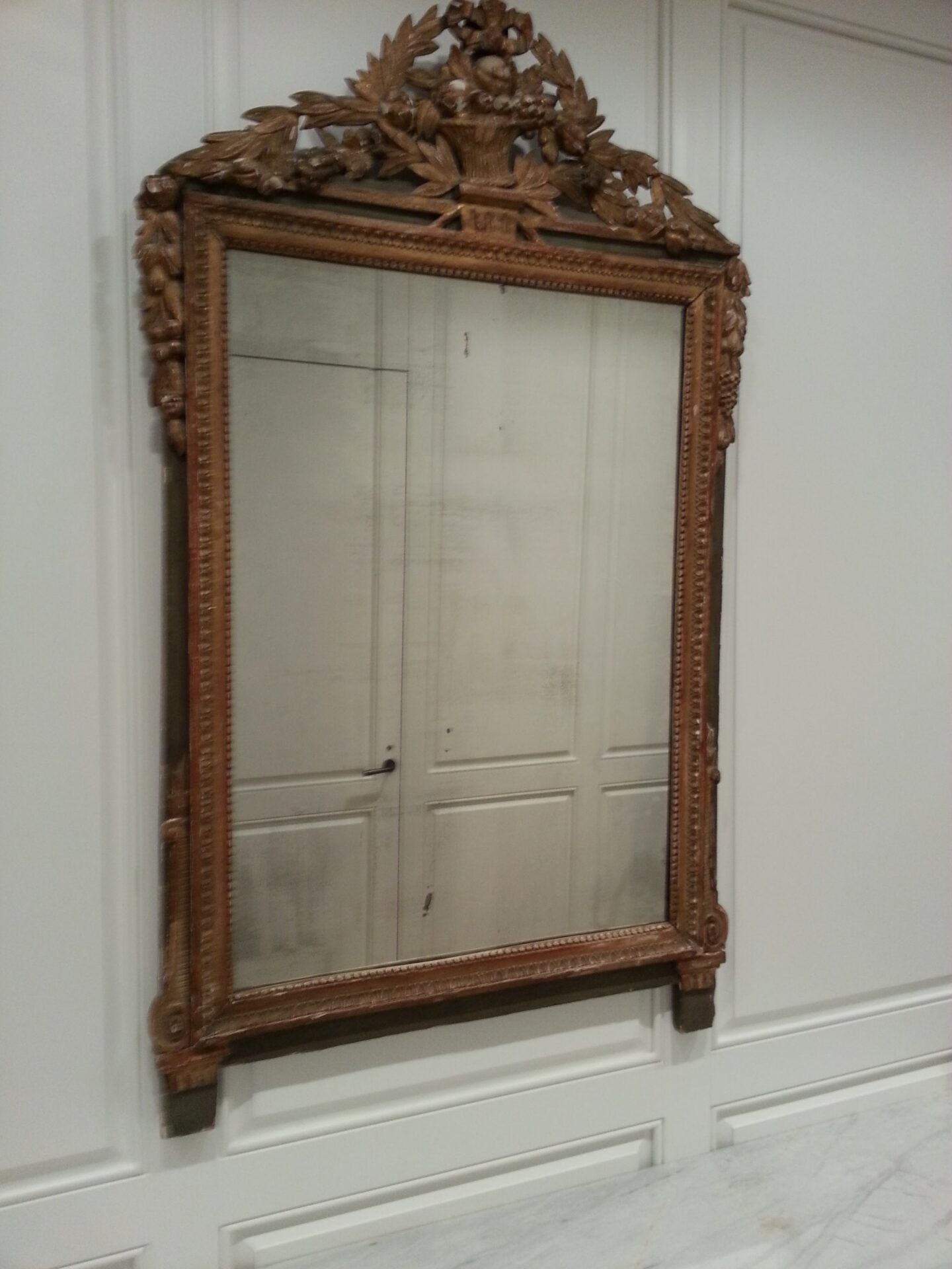A mirror hanging on the wall in front of a white wall.